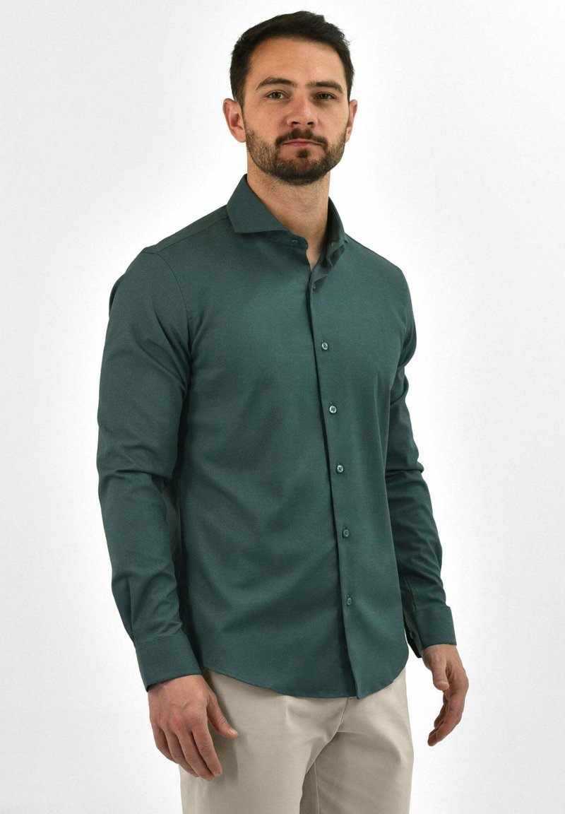 Groen overhemd met lange mouwen van gladde stof, met een knoopsluiting aan de voorkant, een getailleerde pasvorm en een klassieke kraag. Eenvoudig ontwerp zonder patronen.