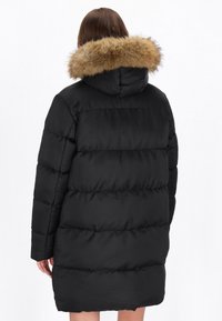 Sort pufferjakke med hætte og faux fur-kant, quiltet design og mid længde. Blød tekstur med polstret isolering.