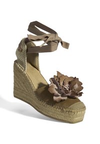 Braune Espadrille-Wedgesandale mit Textiloberfläche, dekorativem Blumenakzent und gekreuzten Ripsband-Trägern. Plattformboden aus Jute.