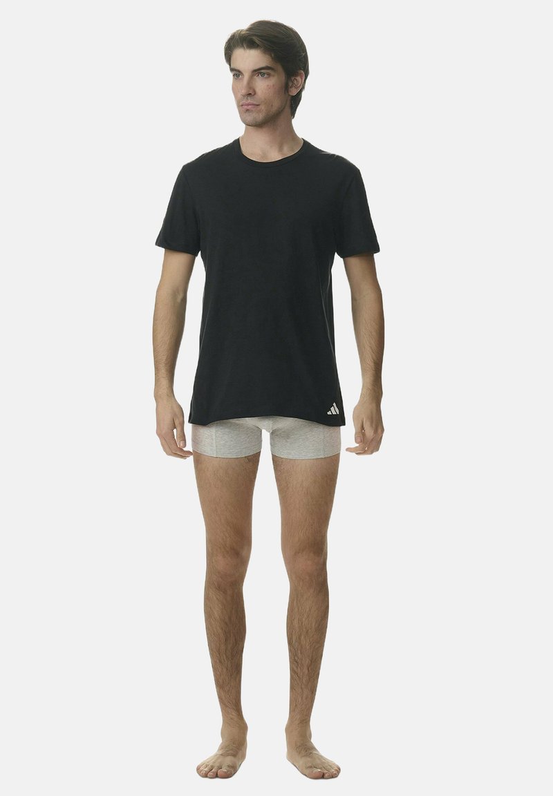 T-shirt noir à manches courtes en coton, associé à des boxers gris clair. Design simple, sans motifs, et petit logo sur le t-shirt.