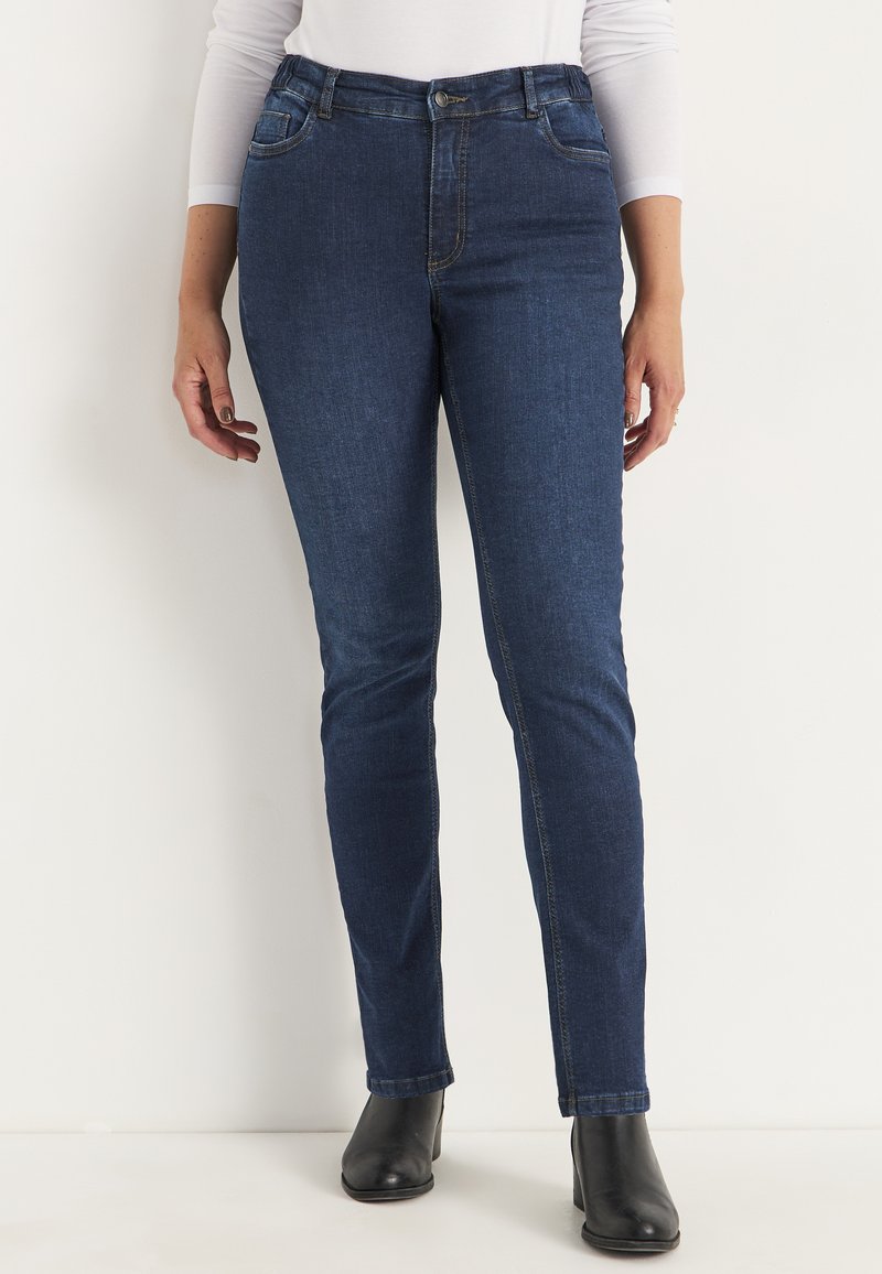 Höga jeans i mörkblå denim med en slät yta, försedda med framfickor och knappstängning, som kompletterar svarta ankelstövlar.