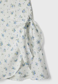 Florales Wickelkleid aus leichtem Stoff, mit einem hellen Hintergrund und blauen sowie grünen Blumenmustern, in der Taille gebunden.