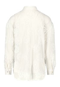 Chemise blanche à manches longues avec broderie florale texturée, poignets boutonnés et col classique, vue de dos.