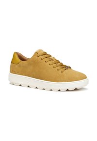 Sneaker in suede beige con suola in gomma bianca, caratterizzato da lacci marroni, punta tonda e un morbido accento giallo sul tallone.