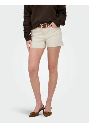 Vrouw draagt beige denimshorts met onafgewerkte zomen, een bruine riem, een bruin lang mouwtopje en bruine slingbacks met hak.