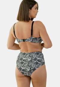 Ensemble de bikini noir et blanc avec un motif floral, bretelles réglables et bas taille haute à texture lisse.