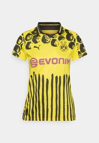 Žltý športový dres s čiernym zvieracím vzorom a vertikálnymi pruhmi. Obsahuje golier, logo Puma a branding Evonik v ružovej farbe.