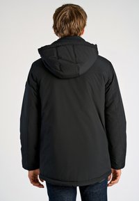Giacca nera con cappuccio, dal design imbottito, caratterizzata da una texture liscia e polsini elasticizzati, che si estende fino ai fianchi.