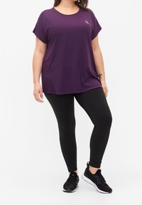 Purple short-sleeve top with a round neck and a logo. Worn with black leggings and black athletic shoes, featuring a sleek design.