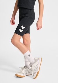 Mörkgrå idrottsshorts med vit chevron-design på sidan,PARAD med gråa och vita sneakers och vita ribbade crew-strumpor.