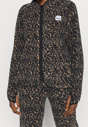 Leopardmønstret, blød lynlåstrøje og matchende bukser med tommelhuller båret af en person, med en hvid logo-patch på brystet.