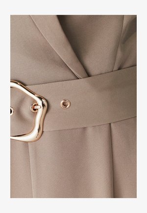 Khakifarbener Stoffgürtel mit einer großen, abstrakt geformten goldenen Schnalle. Glatte Textur mit Nähdetails entlang der Kanten.