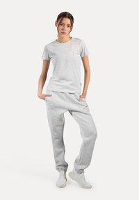 Grå bomulds T-shirt med rund hals, kombineret med grå bomulds joggers med tapered ben og sidelommer. Hvide sneakers fuldender looket.