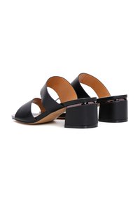 Black leather block-heeled mules with a minimal design, featuring two wide crossover straps and a smooth beige insole.