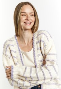 Crème cardigan met lavendelstrepen, gebreide textuur, open voorkant en geribbelde manchetten. Draag het over een beige top, heeft een relaxte pasvorm.