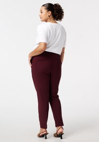 Bordeaux op maat gemaakte broek met een slank ontwerp, voorzien van achterzakken. Gepaard met een losvallend wit T-shirt met korte mouwen en hielen met luipaardprint.