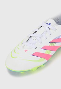 Witte voetbalschoenen met roze en blauwe accenten. Heeft een gestructureerd oppervlak, meerdere ventilatiegaten en felgroene noppen.