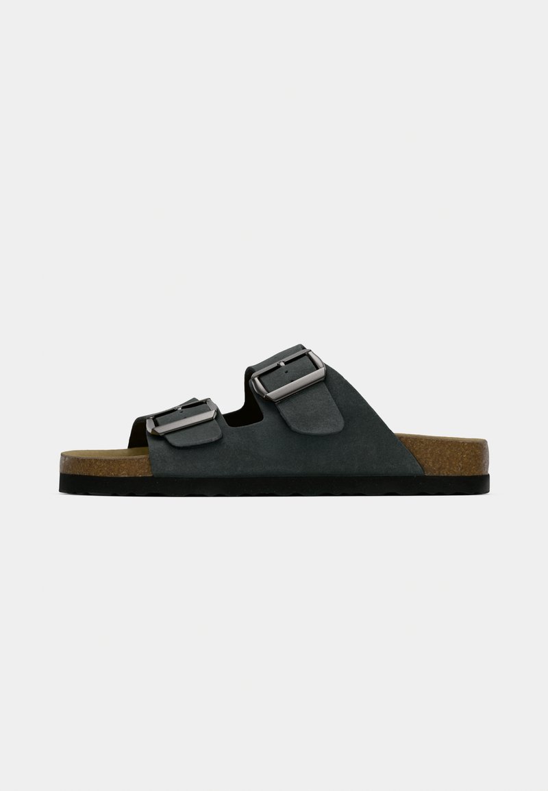 Black two-strap sandal with adjustable buckles, cork footbed, and textured rubber sole. Simple design with an open-toe structure.