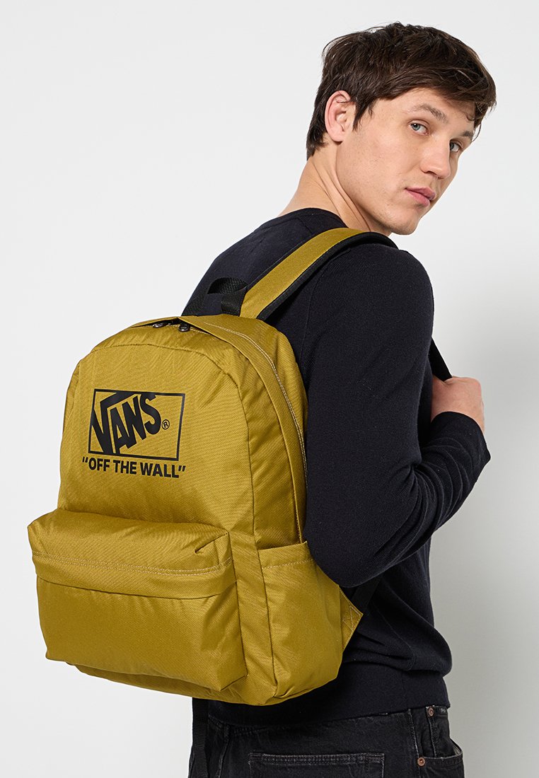 Mochila de tela amarilla con un gran logo, correas acolchadas, doble cremallera y bolsillo delantero, con una superficie texturizada y forma rectangular.