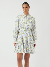 Robe florale en tissu blanc avec des fleurs bleues et vertes, manches longues bouffantes, col et jupe à volants. Comprend une ceinture assortie.