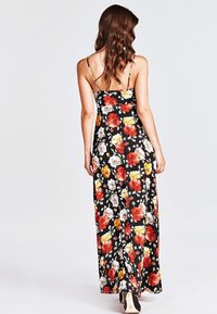 Robe longue à base noire avec un motif floral coloré en rouge, jaune et blanc. Bretelles spaghetti ajustables et design fluide.