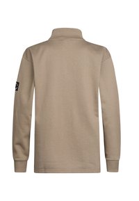 Beige polo tričko s dlouhým rukávem, límečkem, žebrovanými manžetami a nášivkou s logem na levém rukávu. Měkký materiál se hladkým povrchem.