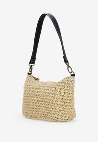 Borsa a tracolla in paglia intrecciata di colore crema, dalla forma curvata, completata da una tracolla in pelle nera e dettagli in ottone.