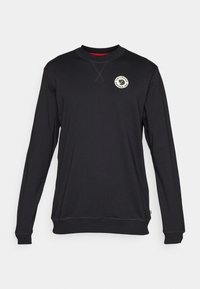 Sudadera negra de manga larga con cuello redondo, presenta un logo en el pecho, puños acanalados y una textura lisa. Detalle interior del cuello en rojo.