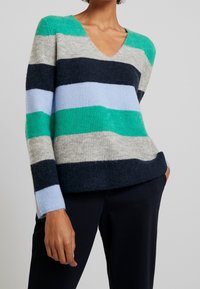 Pull rayé à col en V, aux teintes bleu sarcelle, gris, marine et bleu clair ; fabriqué en tissu tricoté texturé, manches longues, coupe décontractée.