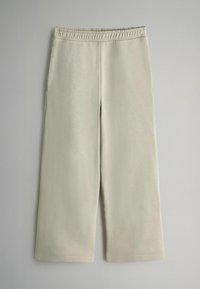 Pantalones de chándal cortos color beige claro con una cinturilla elástica, bolsillos laterales y una tela suave y texturizada. Presenta un corte de pierna recta.