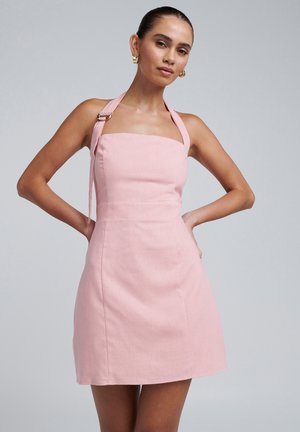 Pink linen dress with a square neckline, halter straps, and a fitted bodice. Features a flared skirt and minimal stitching details.