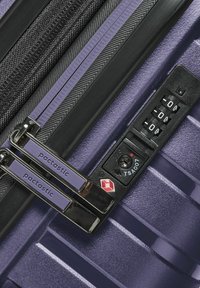 Maleta dura púrpura con doble cremallera negra, cerradura de combinación, superficie texturizada y marca "pactastic" en los tiradores de las cremalleras.