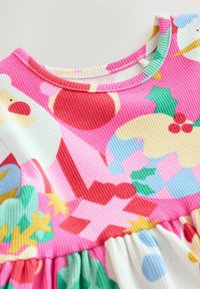 Bunt gefärbtes Baumwolkleid mit gerippter Textur, das einen rosa Oberteil und einen ausgestellten weißen Rock mit bunten, festlichen Mustern zeigt.