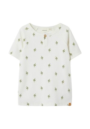 T-shirt blanc à manches courtes côtelé avec un col rond, présentant un motif de feuilles vertes et un détail de bouton en bois au niveau du cou.