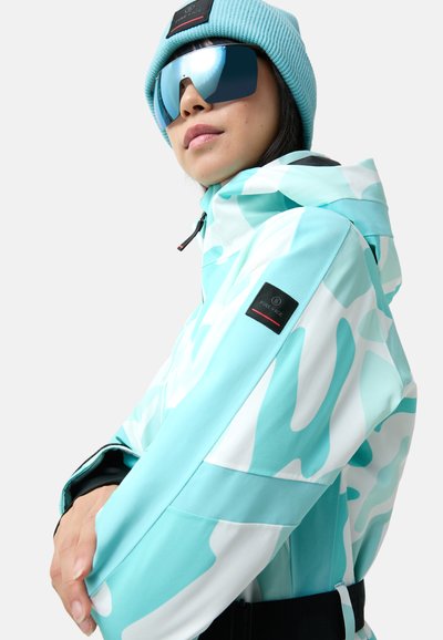 Eine türkis-weiße Jacke im Camouflage-Muster aus einem glatten, leichten Stoff, mit Kapuze und Logopatch am Ärmel.