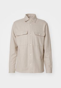 Beżowa koszula z długim rękawem wykonana z materiału o fakturze. Posiada zapięcie na guziki z przodu, dwie kieszenie na piersi oraz klasyczny kołnierz.