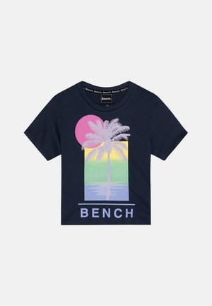 Chemise bleu marine à manches courtes avec graphique de palmier rose, jaune, vert et lavande, et texte « BENCH » sous le motif.
