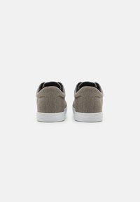 Gray canvas sneakers with a textured surface and white rubber soles. Features a low-profile design and padded collar for comfort.