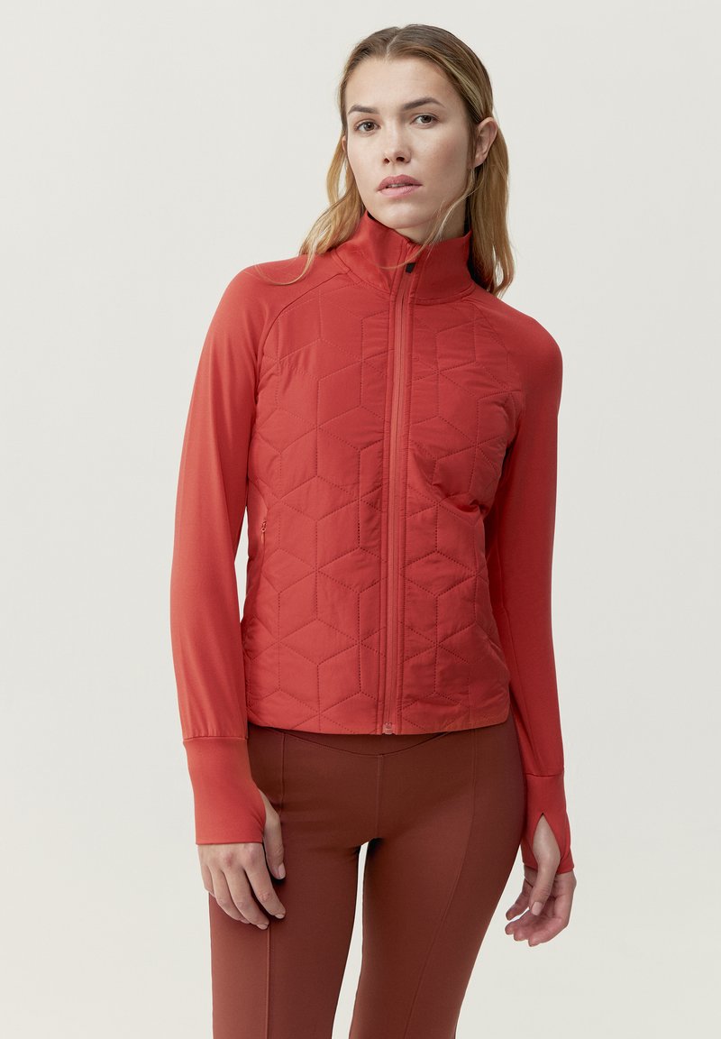 Punainen tikattu takki, jossa on korkea kaulus, vetoketjusulku ja pitkät hihat, joissa on peukalonreiät. Tasainen kankaan rakenne ja istuva muotoilu.