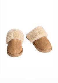 Pantofole in suede color sabbia con un morbido risvolto in pelliccia sintetica beige, punta arrotondata e suola piatta in gomma. Tessuto liscio con dettagli di cucitura lungo i bordi.