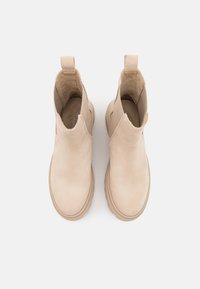 Beige Stiefeletten aus glattem Wildleder mit elastischen seitlichen Einsätzen und einer Zuglasche. Dicke, leichte Sohle mit runder Zehenpartie.