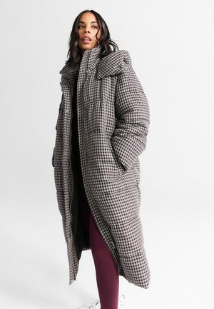 Puffer coat in a brown and black houndstooth pattern, with a high collar, oversized fit, and front zipper closure. Features side pockets.
