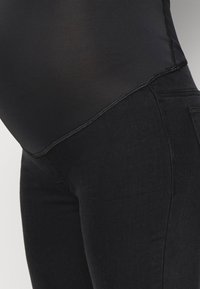 Bodysuit preto com uma parte superior suave e transparente e uma parte inferior opaca e ajustada. Apresenta costuras planas e um design de cintura alta.