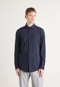 Camisa de manga larga azul marino con cuello abotonado, tapeta frontal con botones y una textura de tela suave y ligera.