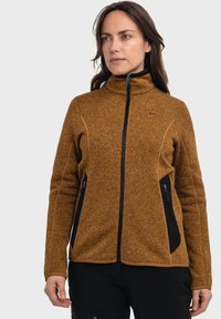 Fleecejacke in strukturiertem Braun mit hohem Kragen, schwarzen Reißverschlusstaschen und kontrastierenden Akzenten entlang des Saums und der Bündchen.