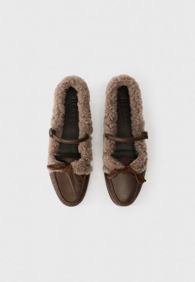 Brown leather moccasin-style shoes with fluffy tan lining, a brown strap, and laces. Textured exterior and soft interior for comfort.