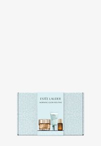 Estee Lauder Morning Glow-rutinens förpackning har en ljusblå blommönsterdesign och visar tre hudvårdsprodukter med gulddetaljer.