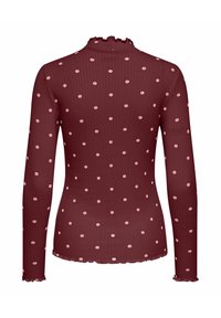 Top met lange mouwen in kastanjebruin, met een geribbelde structuur en lichtroze stippen. Halslijn en zoom met ruches voor extra detail.