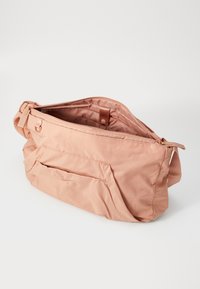 Roze stoffen tas met een geperforeerde bovenkant, textuur oppervlak en een voorvak. Voorzien van een schouderband en een binnenvoering in bijpassende kleur.