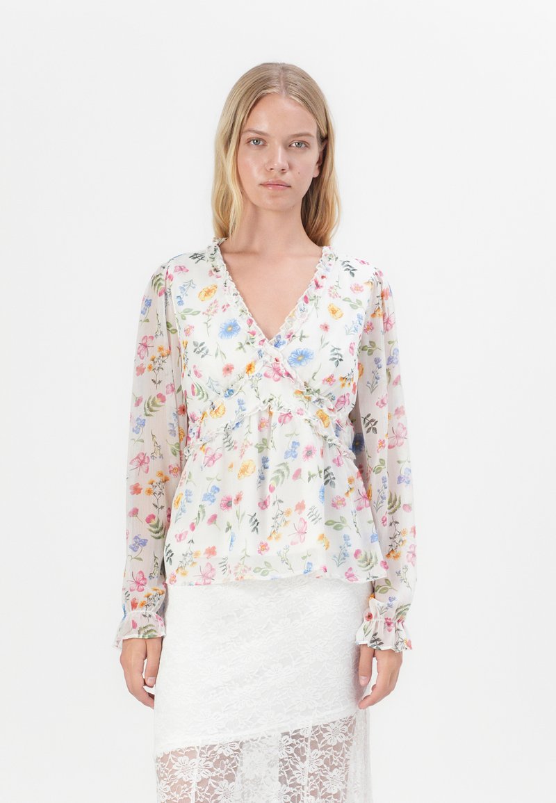 Blusa avvolgente floreale in tessuto leggero e trasparente, con scollatura a V, maniche lunghe e dettagli smerlati. Presenta motivi floreali multicolori.